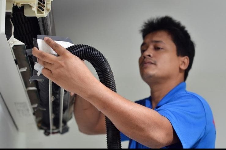 Kai Leong servicing an aircon unit in a Tampines flat